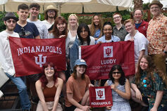 A group of IU students poses for a picture in Greece holding IU Indianapolis and Luddy flags.